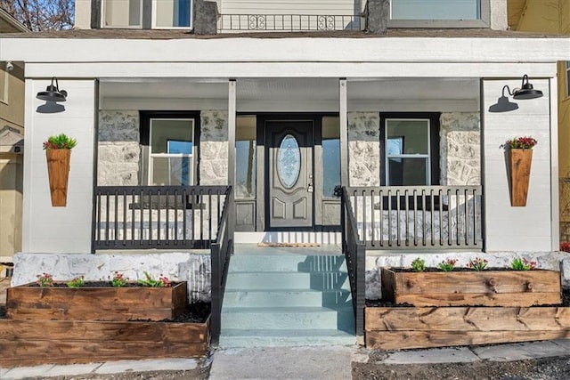 doorway to property with a porch and concrete block siding