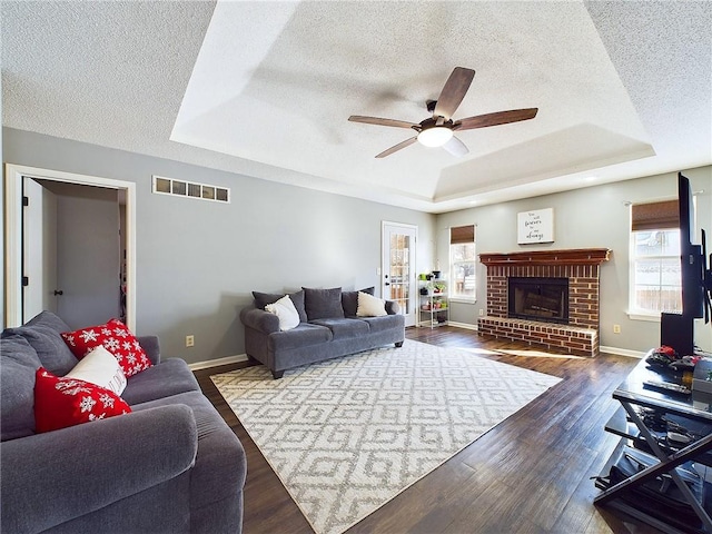 living room featuring wood finished floors, a raised ceiling, visible vents, and baseboards