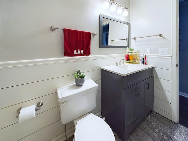 half bathroom featuring toilet, a wainscoted wall, and vanity