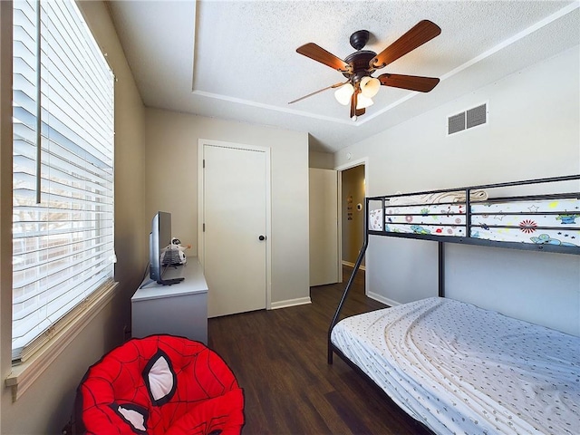 bedroom featuring a textured ceiling, ceiling fan, dark wood-style flooring, and visible vents