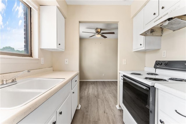 kitchen with light wood finished floors, electric range, under cabinet range hood, white cabinetry, and a sink