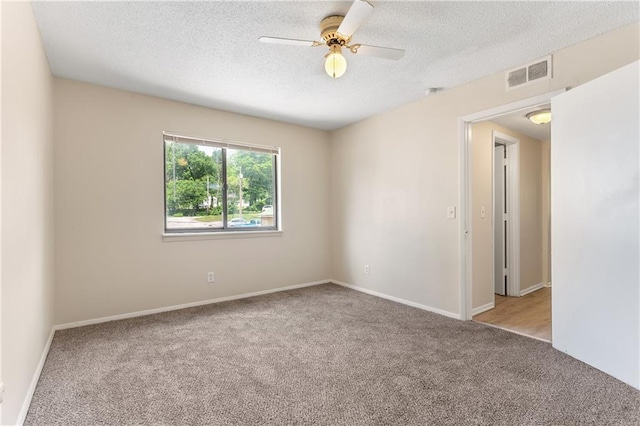 carpeted empty room featuring a textured ceiling, baseboards, visible vents, and a ceiling fan