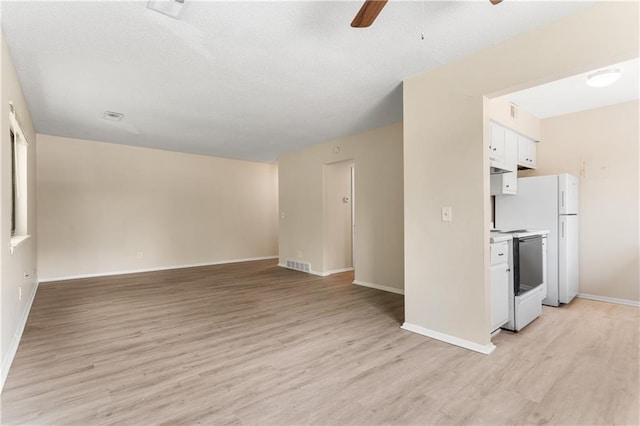 interior space featuring light wood-style floors, visible vents, ceiling fan, and baseboards