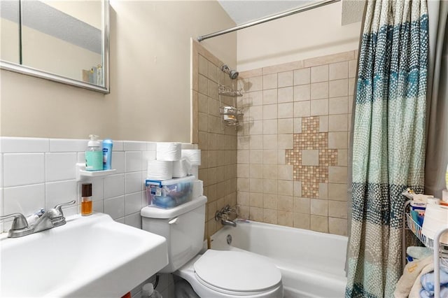 bathroom with shower / tub combo, a sink, toilet, and tile walls