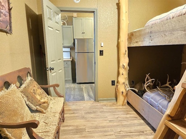 bedroom featuring light wood finished floors and freestanding refrigerator