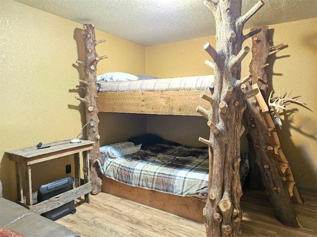 bedroom with a textured ceiling and wood finished floors