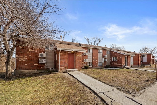 view of front facade with entry steps, brick siding, and a front yard