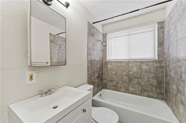 full bathroom featuring toilet, a textured wall, vanity, and bathing tub / shower combination