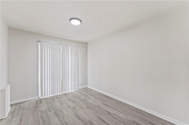 spare room featuring light wood finished floors and baseboards