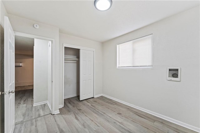 unfurnished bedroom with a closet, light wood-style flooring, and baseboards