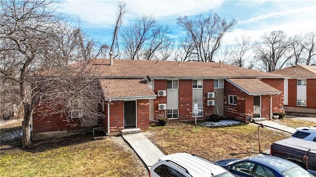 view of front of house with brick siding, roof with shingles, and a front yard