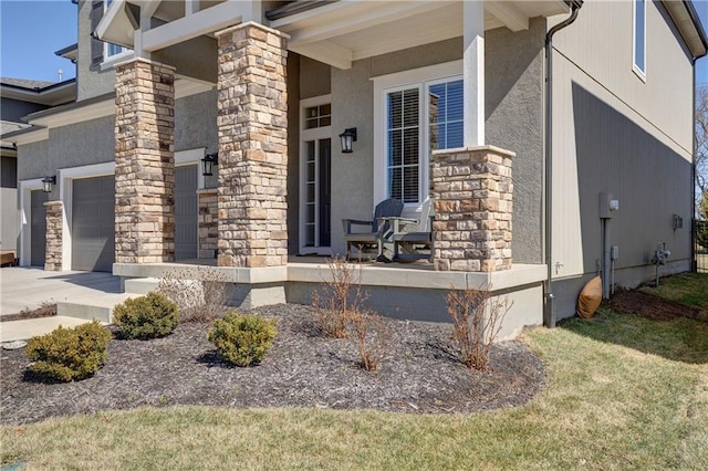 doorway to property with stone siding, stucco siding, a porch, and concrete driveway