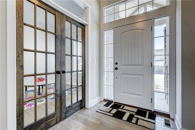 foyer entrance featuring wood finished floors, visible vents, and baseboards