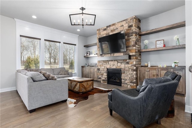 living room with a fireplace, baseboards, an inviting chandelier, and wood finished floors