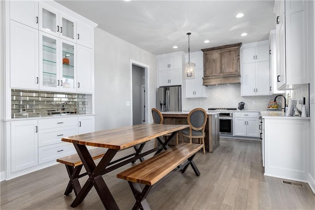 kitchen featuring tasteful backsplash, white cabinetry, appliances with stainless steel finishes, light wood finished floors, and light countertops