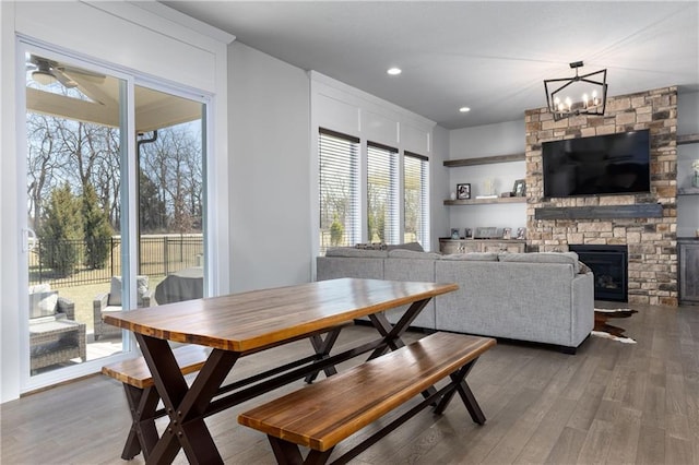 dining area featuring recessed lighting, a notable chandelier, wood finished floors, and a fireplace