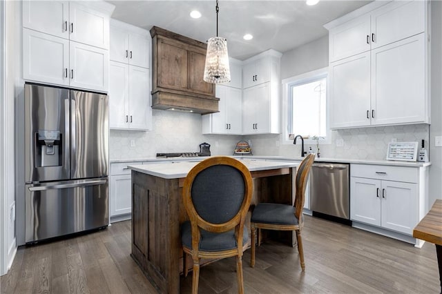 kitchen with a kitchen island, dark wood finished floors, light countertops, stainless steel appliances, and white cabinetry