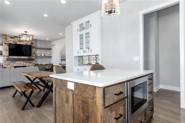 kitchen featuring stainless steel microwave, wood finished floors, an inviting chandelier, and white cabinets