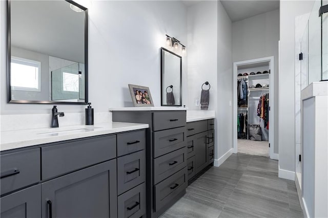 bathroom with vanity, a shower stall, a spacious closet, and baseboards