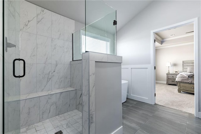 full bath featuring a marble finish shower, a freestanding bath, vaulted ceiling, wainscoting, and a decorative wall