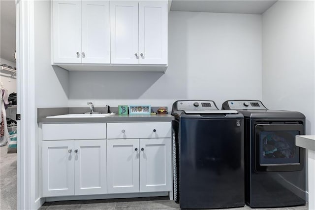 clothes washing area featuring washer and dryer, cabinet space, and a sink