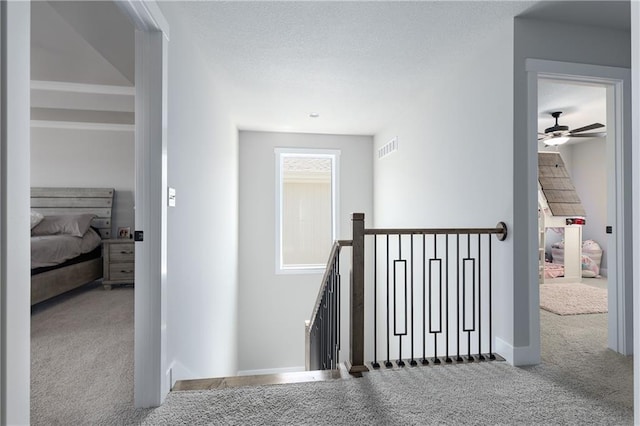 stairway with visible vents, baseboards, carpet, and a textured ceiling