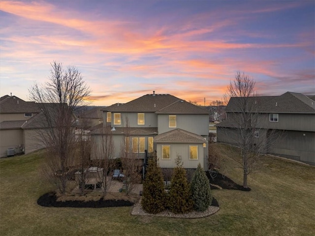 back of property with a lawn and a shingled roof