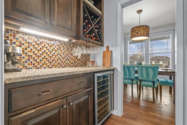 bar featuring pendant lighting, backsplash, wood finished floors, wine cooler, and a bar