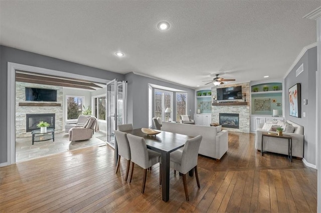 dining space featuring a stone fireplace, dark wood-type flooring, and a textured ceiling