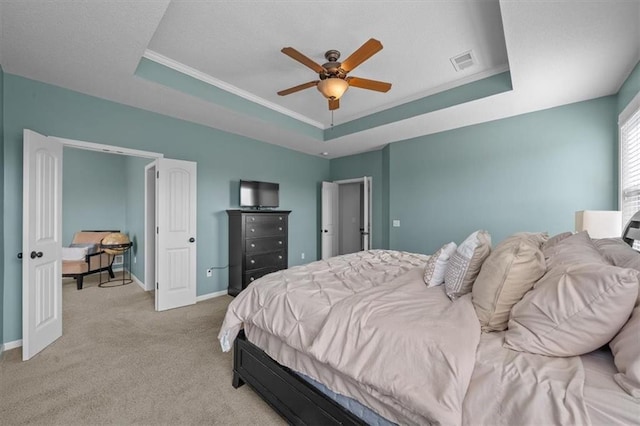 bedroom with visible vents, crown molding, baseboards, light carpet, and a raised ceiling