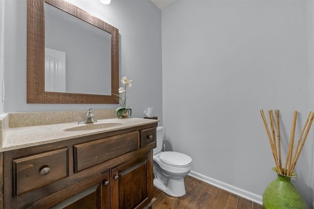 half bathroom featuring baseboards, toilet, wood finished floors, and vanity