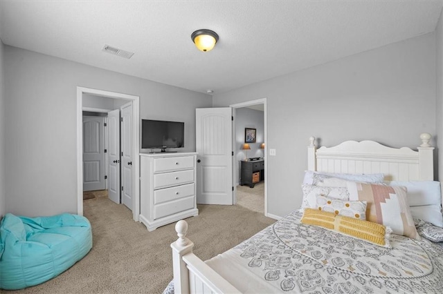 carpeted bedroom featuring visible vents, a textured ceiling, and baseboards