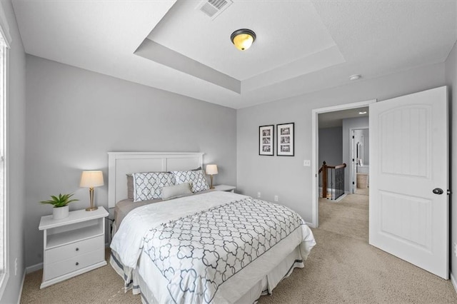 bedroom featuring visible vents, light colored carpet, a raised ceiling, and baseboards