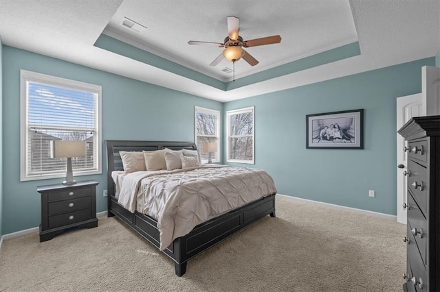 bedroom with multiple windows, a raised ceiling, visible vents, and light carpet