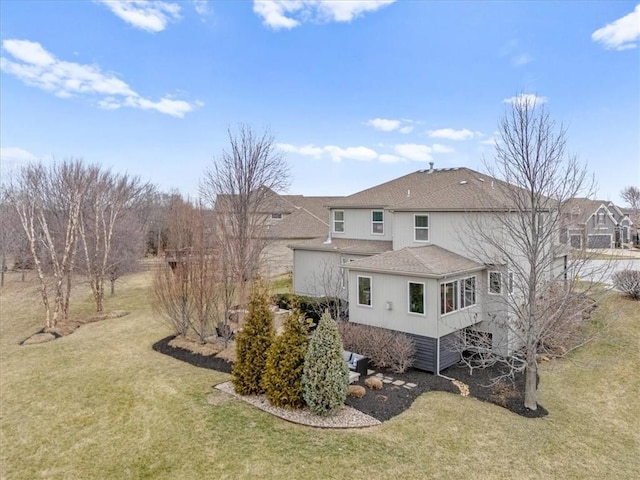 rear view of house with a yard and a shingled roof