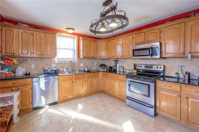 kitchen featuring dark countertops, appliances with stainless steel finishes, backsplash, and a sink