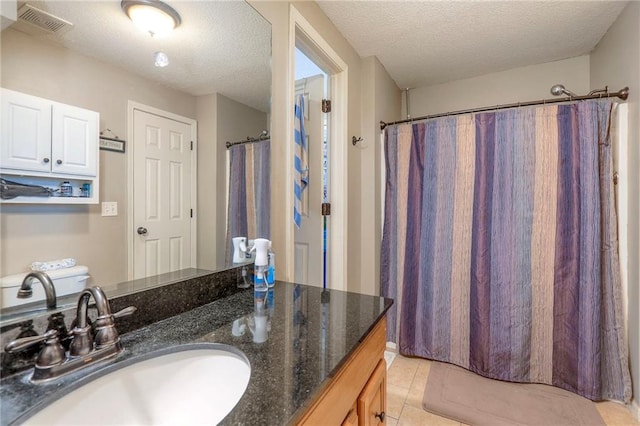 full bath with a textured ceiling, vanity, visible vents, and tile patterned floors