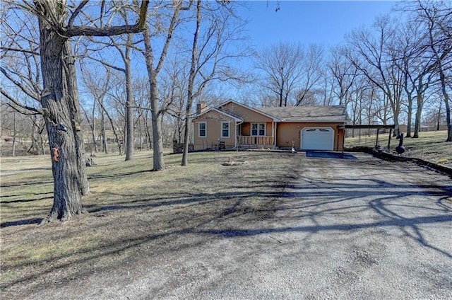 view of front of property with a front lawn, covered porch, a chimney, a garage, and driveway