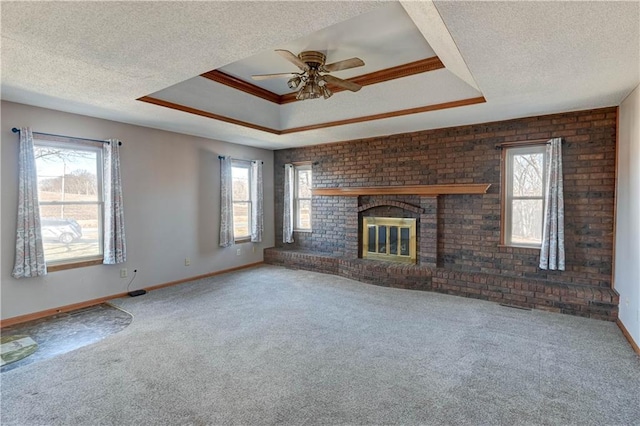 unfurnished living room featuring a wealth of natural light, a brick fireplace, a textured ceiling, and a raised ceiling