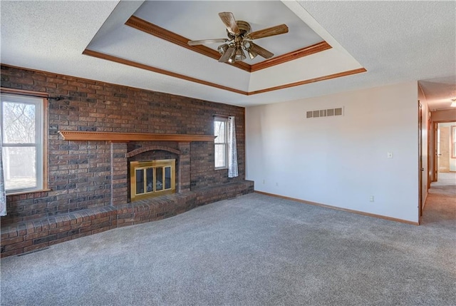 unfurnished living room featuring a fireplace, a textured ceiling, carpet, and a tray ceiling