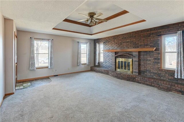 unfurnished living room featuring a tray ceiling, a textured ceiling, carpet floors, a fireplace, and baseboards