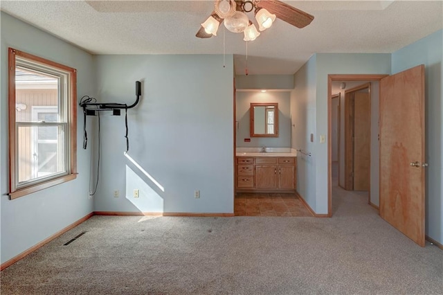 unfurnished bedroom featuring visible vents, baseboards, light carpet, a textured ceiling, and a sink