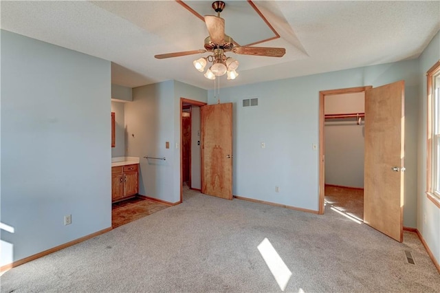 unfurnished bedroom featuring connected bathroom, baseboards, visible vents, and light carpet