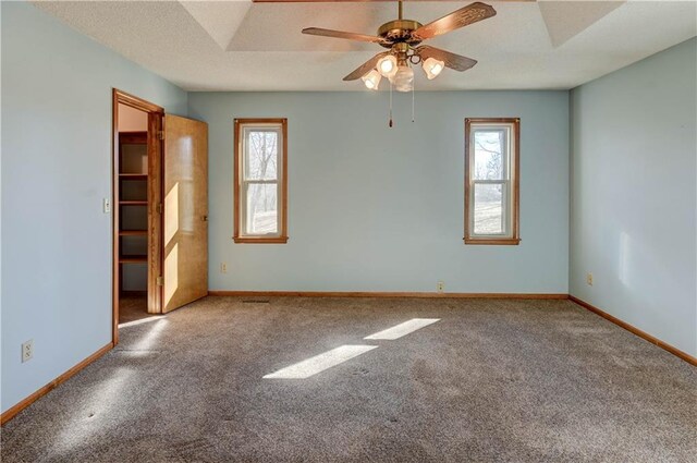 carpeted empty room with a wealth of natural light, a textured ceiling, baseboards, and a ceiling fan