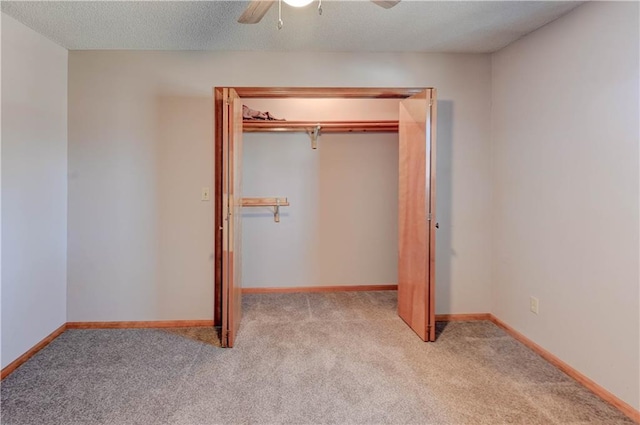 unfurnished bedroom with a textured ceiling, a closet, carpet, baseboards, and ceiling fan