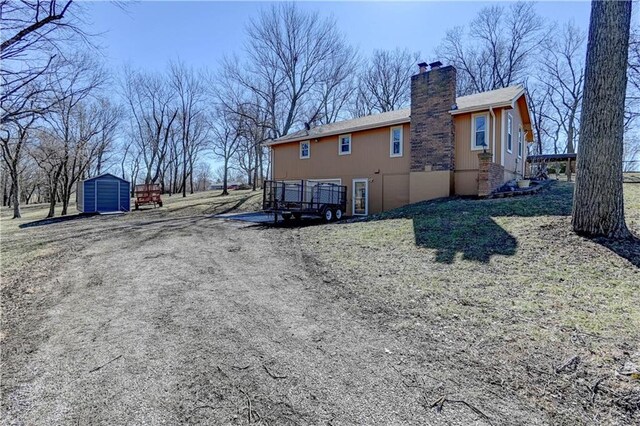 rear view of house featuring an outbuilding, a shed, and a chimney