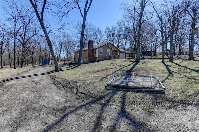 view of property exterior with an outbuilding, driveway, a shed, a yard, and a chimney