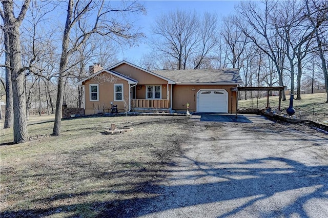 view of front of property featuring a porch, an attached garage, driveway, and a chimney