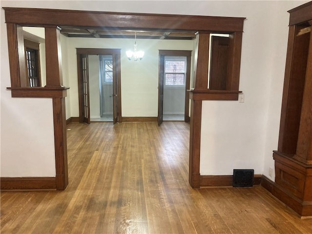 interior space featuring a notable chandelier, baseboards, and wood finished floors