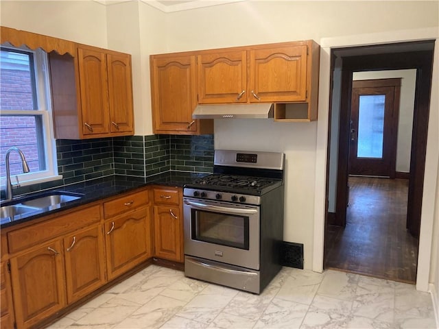 kitchen with marble finish floor, stainless steel gas range oven, under cabinet range hood, and a sink